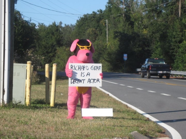 Pink dog holding Richard Gere sign